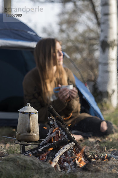 Frau beim Zelten am Lagerfeuer im Wald