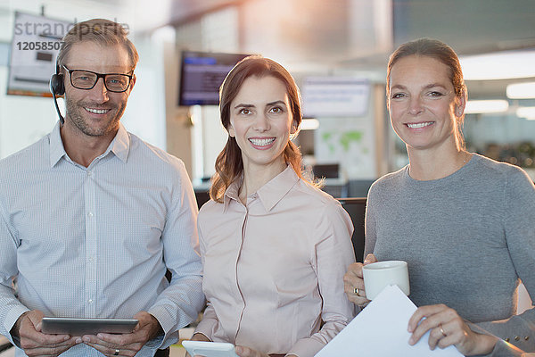 Portrait lächelnde  selbstbewusste Geschäftsleute mit digitalem Tablet und Kaffee im Büro