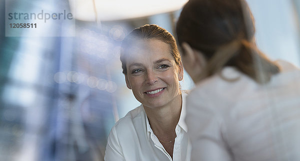 Lächelnde Geschäftsfrau hört einem Kollegen zu