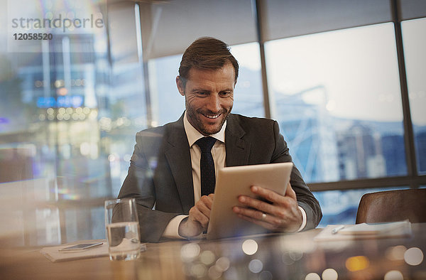 Lächelnder Geschäftsmann mit digitalem Tablet im Konferenzraum