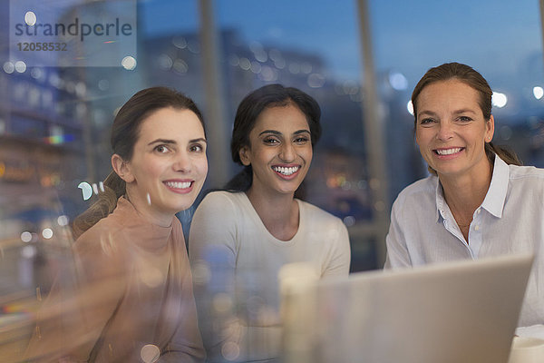 Porträt einer lächelnden  selbstbewussten Geschäftsfrau  die in einem Konferenzraum an einem Laptop arbeitet