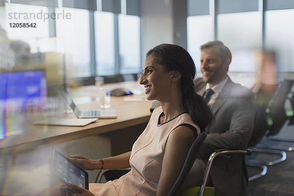 Lächelnde Geschäftsfrau mit digitalem Tablet in einer Konferenzraumbesprechung