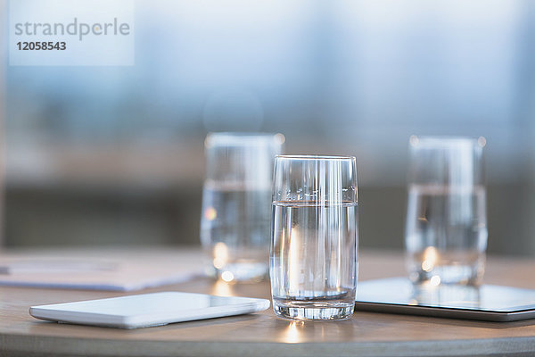 Wasser in Gläsern neben digitalen Tabletten auf dem Tisch