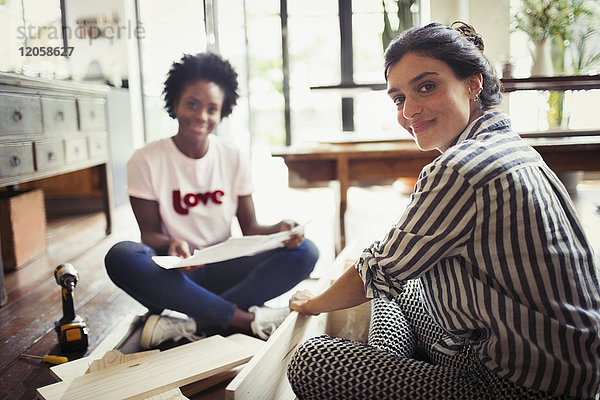 Portrait lächelnde  selbstbewusste Frauen mit Anleitung zum Zusammenbau von Möbeln