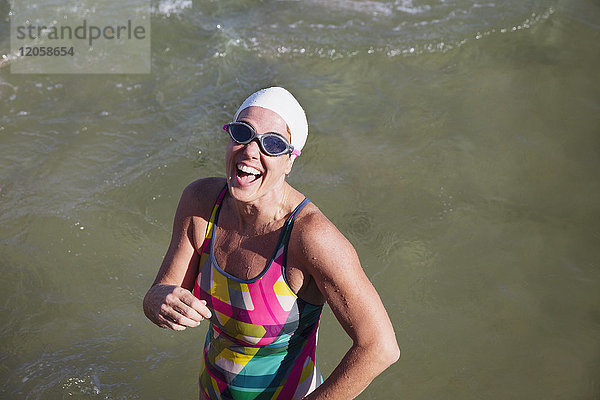 Porträt einer lachenden  selbstbewussten Schwimmerin  die im Ozean watet