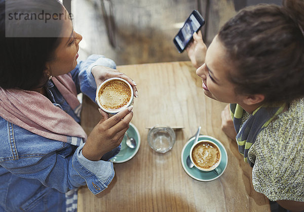 Freundinnen trinken Kaffee und telefonieren im Café