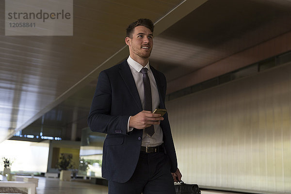 Geschäftsmann zu Fuß mit Smartphone in der Büro-Lobby