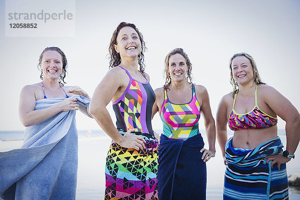 Portrait lächelnde  selbstbewusste Schwimmerinnen  die mit Handtüchern abtrocknen.