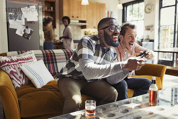 Männliche Freunde trinken Bier und spielen Videospiel im Wohnzimmer