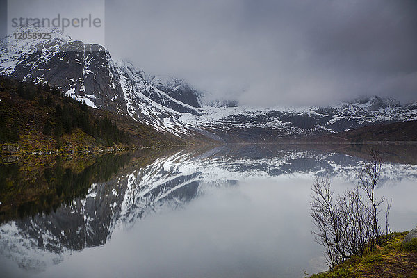 Spiegelung von verschneiten  zerklüfteten Bergen im Wasser  Storvatnet  Lofoten  Norwegen