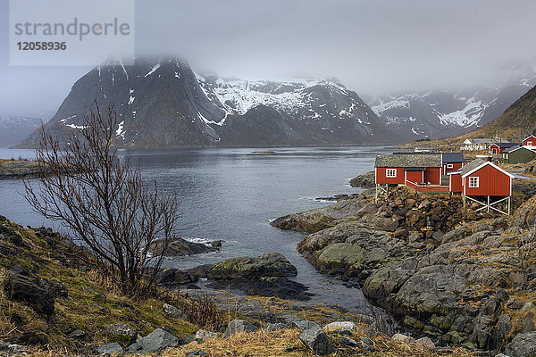 Fischerdorf am Wasser unter verschneiten  zerklüfteten Bergen  Hamnoya  Lofoten  Norwegen