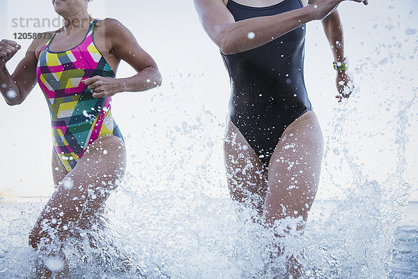 Weibliche Freischwimmerinnen beim Laufen und Plantschen im Meer
