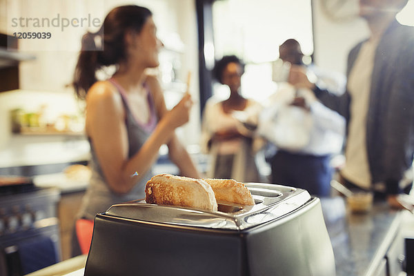 Freund Zimmergenossen sprechen hinter Toast in Toaster in der Küche