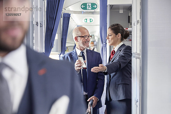 Flugbegleiterin hilft Geschäftsmann mit digitaler Bordkarte im Flugzeug