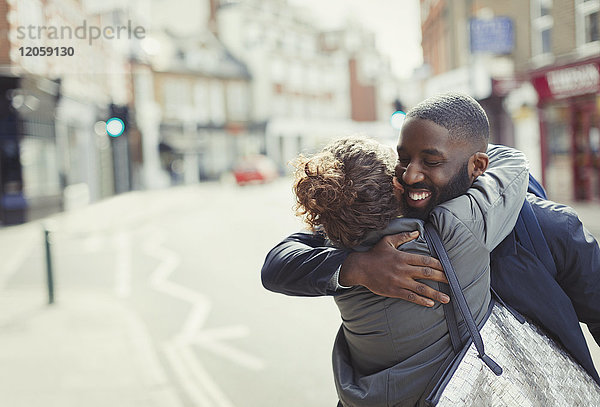Fröhliches  liebevolles junges Paar  das sich auf einer sonnigen Stadtstraße umarmt.