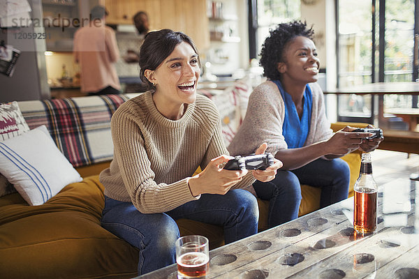 Lachende Freundinnen beim Videospiel auf dem Wohnzimmersofa