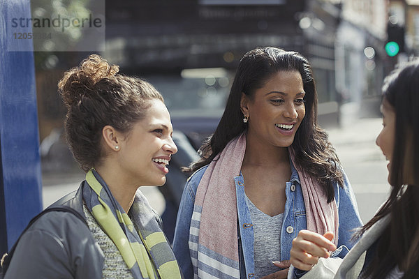 Lächelnde Freundinnen im Gespräch auf der Straße