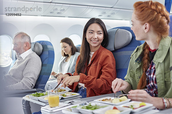 Frauen  die im Flugzeug essen und sich unterhalten