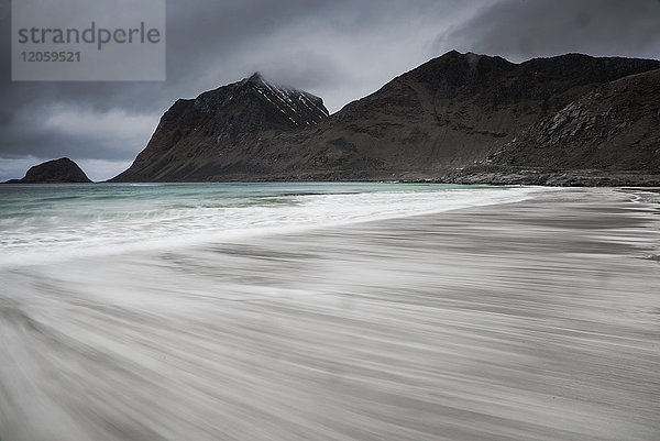 Verschwommene Meeresströmung unter zerklüfteten Bergen  Haukland Beach  Lofoten  Norwegen