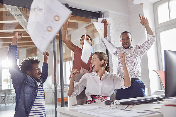 Überbordende Geschäftsleute feiern  werfen Papierkram ins Büro