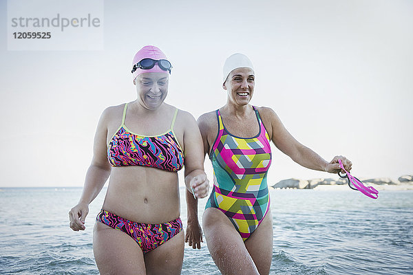 Lächelnde Schwimmerinnen  die im Ozean waten