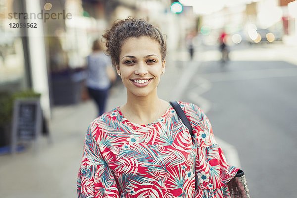 Portrait lächelnde junge Frau auf urbaner Straße