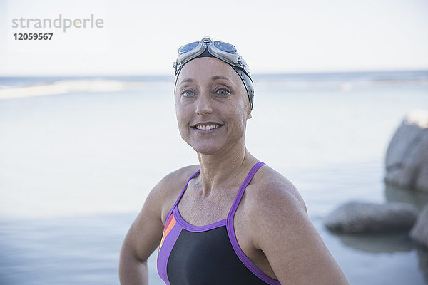 Portrait lächelnde  selbstbewusste Schwimmerin am Meer