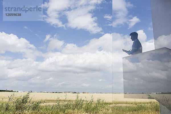 Silhouette Geschäftsmann schriftlich auf modernen Balkon mit Blick auf sonnigen blauen Himmel und Wolken