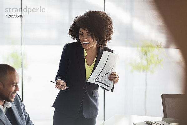 Lächelnde Geschäftsfrau mit Papierkram als Leiterin des Meetings