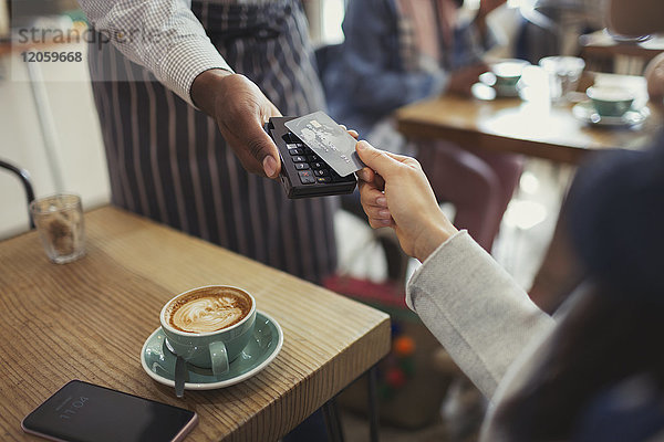 Kunde mit Kreditkartenzahler mit kontaktloser Bezahlung im Cafe