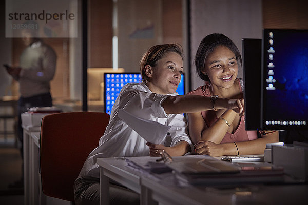 Weibliche Geschäftsfrauen arbeiten nachts spät am Computer im dunklen Büro.