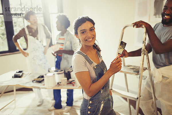 Portrait lächelnde  selbstbewusste Frau beim Malen im Wohnzimmer mit Freunden