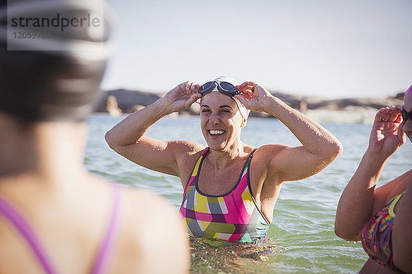 Lächelnde Schwimmerinnen waten im sonnigen Ozean