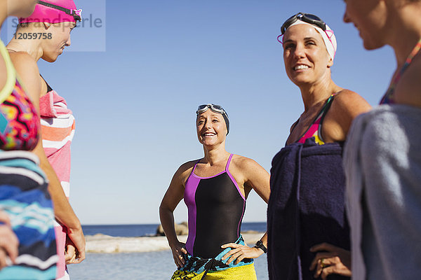 Lächelnde Schwimmerinnen wickelten ihre Handtücher am sonnigen Strand ein.