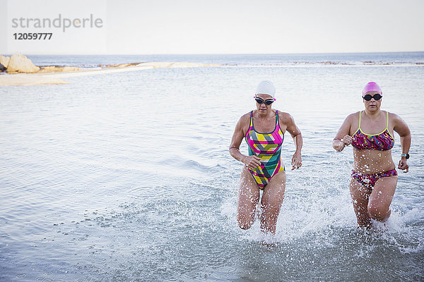 Weibliche Freischwimmerinnen beim Laufen und Plantschen im Meer