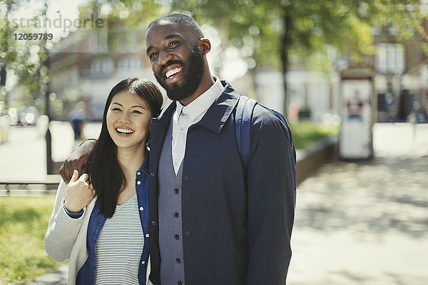 Lächelndes  anhängliches junges Paar im sonnigen Stadtpark