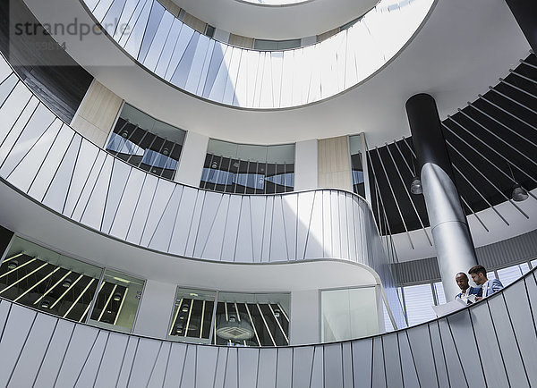 Geschäftsleute diskutieren Papierkram auf architektonischem  modernem Büro-Atrium-Balkon
