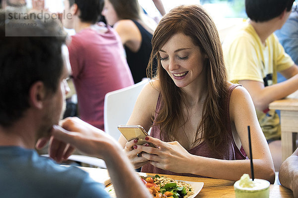 Frau mit Smartphone im Restaurant