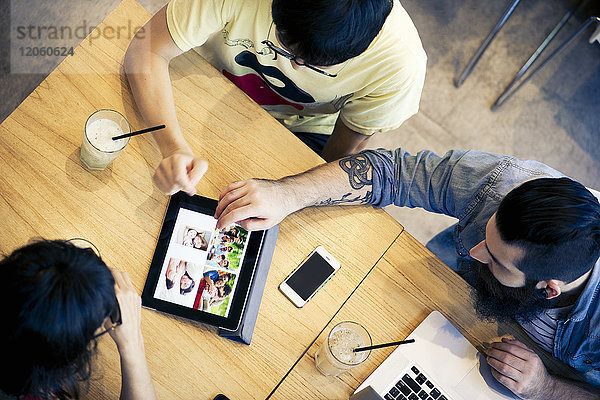 Freunde  die sich gemeinsam im Cafe ein digitales Tablett anschauen