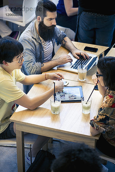 Freunde  die digitale Tablet- und Laptop-Computer im Cafe benutzen