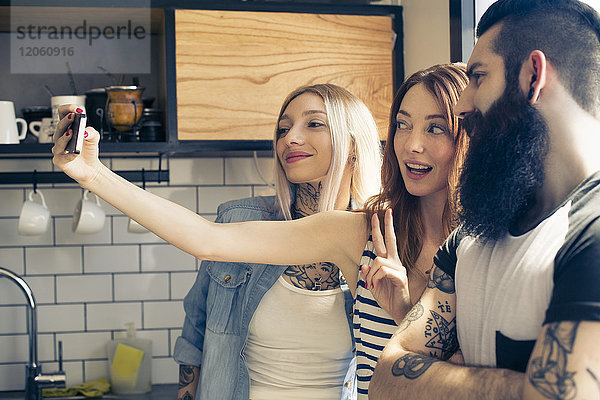 Freunde posieren zusammen für Selfie mit Smartphone