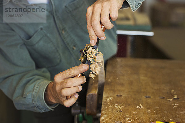Ein Handwerker  der einen Speichenrasierer mit Klinge verwendet  um ein Stück Holz in einer Klemme zu schneiden.
