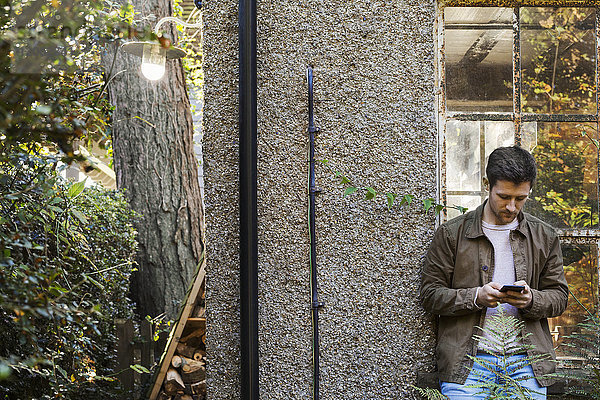 Ein junger Mann  der ein Smartphone benutzt und in einem Innenhof steht.