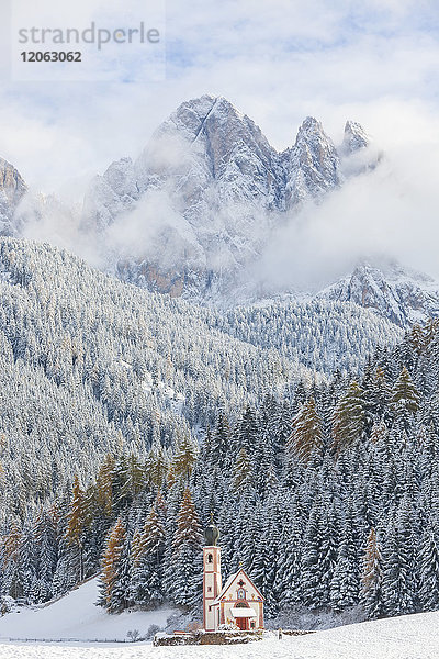 Winterlandschaft mit Kirche  Wald und schneebedeckten Bergen.