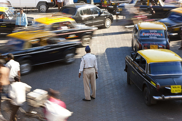 Hochwinkelaufnahme eines Mannes  der mitten auf einer belebten Straße steht  umgeben von Autos und Taxis.