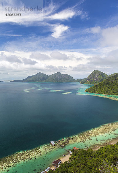 Hochwinkelansicht entlang der Küstenlinie der tropischen Insel  Berge in der Ferne.