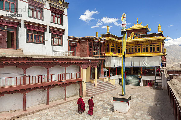 Außenansicht des buddhistischen Klosters mit zwei Mönchen  die über den Innenhof gehen.