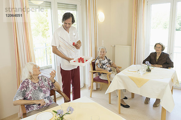 Pflegerin gibt einer älteren Frau im Altersheim Medikamente