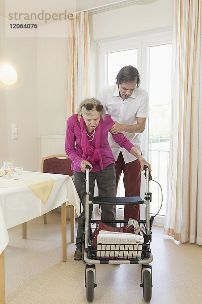 Hausmeisterin hilft einer älteren Frau mit Rollator