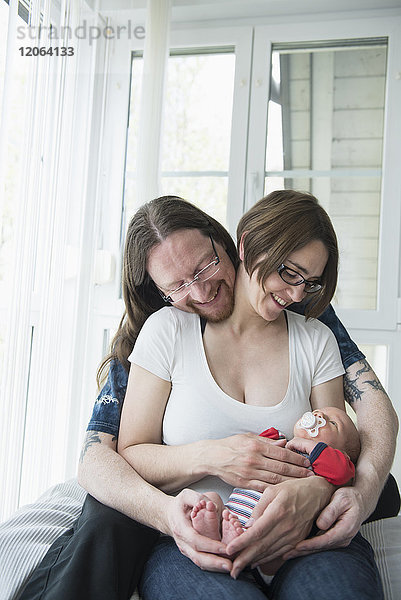 Eltern kuscheln mit neugeborenem Jungen zu Hause